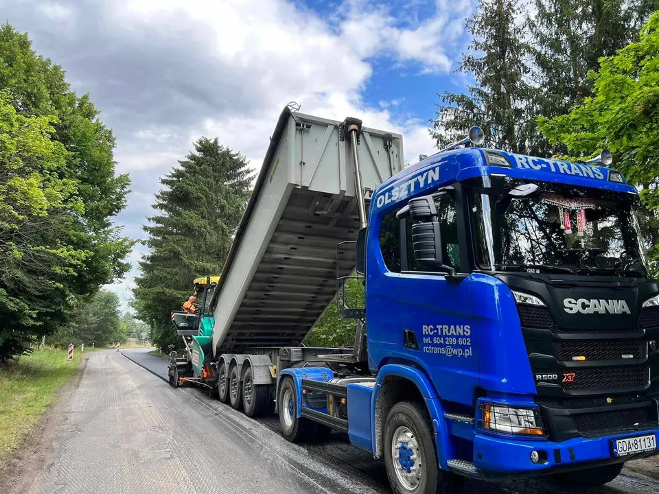 Scania R500 z naczepą wywrotką rozładowująca masę bitumiczną przy układarce asfaltu